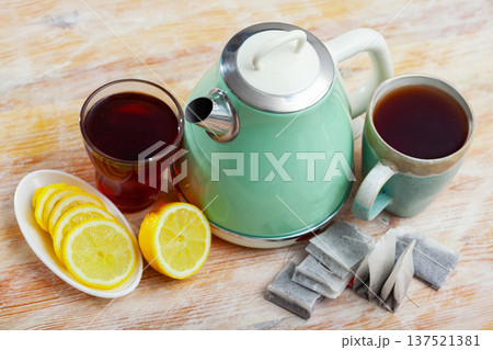 New teapot on table with cup of black tea and sliced lemon 137521381