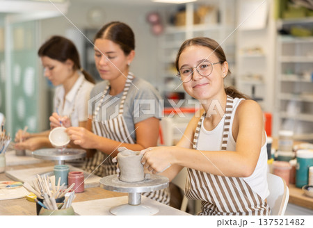 Woman teacher and students sculpt and paint ceramics 137521482