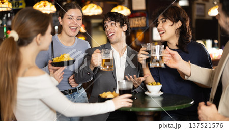 Group of friends at bar talking and drinking beer 137521576