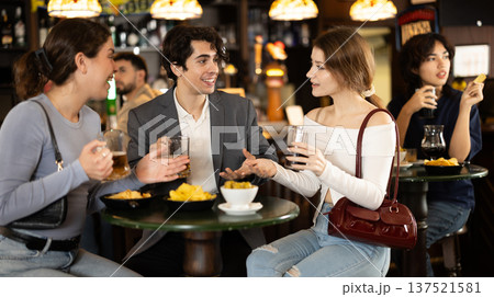 Group of happy friends spending time in bar, having fun while drinking beer and talking Group of happy friends spending time in bar, having fun while drinking beer and talking 137521581