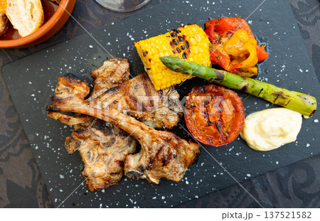 Grilled lamb ribs with sauce and vegetable garnish Grilled lamb ribs with sauce and vegetable garnish 137521582