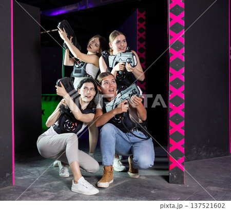 Girls play laser tag, jokingly fight with light weapons Girls play laser tag, jokingly fight with light weapons 137521602