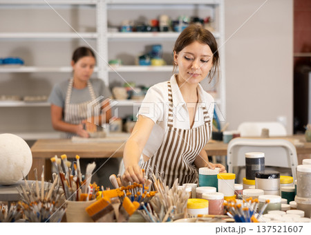 Young girl choosing brush for painting clay product Young girl choosing brush for painting clay product 137521607
