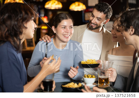 Group of friends at bar talking and drinking beer Group of friends at bar talking and drinking beer 137521658