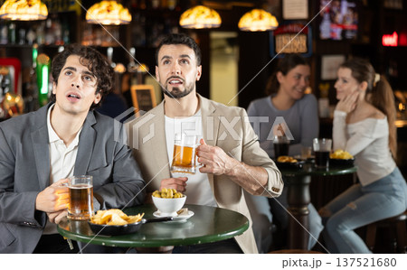 Group of friends hangs out at sports bar, watching teams match 137521680