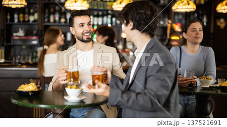 Two men discuss news and business over glass of beer in bar 137521691