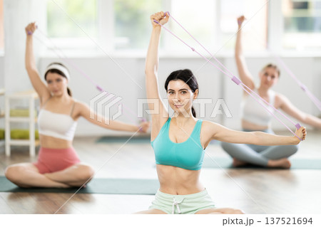 Group of young women doing pilates with loop Group of young women doing pilates with loop 137521694
