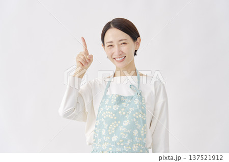 左を指差すエプロンを着た女性　白背景 137521912