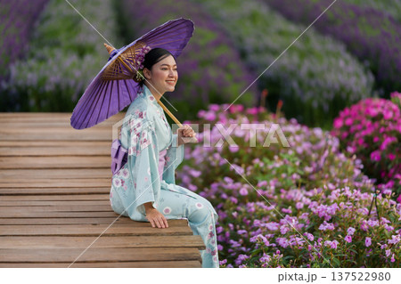 woman in yukata (kimono dress) holding umbrella with flower blooming in garden woman in yukata (kimono dress) holding umbrella with flower blooming in garden 137522980
