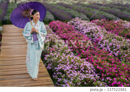 woman in yukata (kimono dress) holding umbrella with flower blooming in garden woman in yukata (kimono dress) holding umbrella with flower blooming in garden 137522981