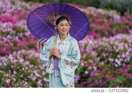 woman in yukata (kimono dress) holding umbrella with flower blooming in garden 137522982