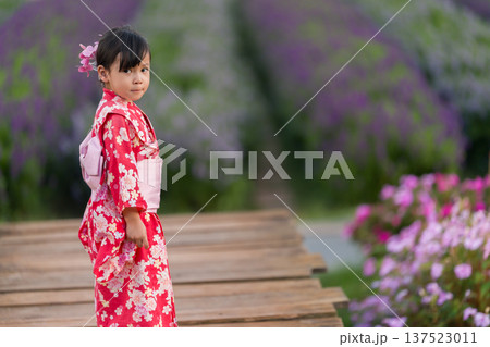 preschool child girl in yukata (kimono dress) with flower blooming in garden 137523011