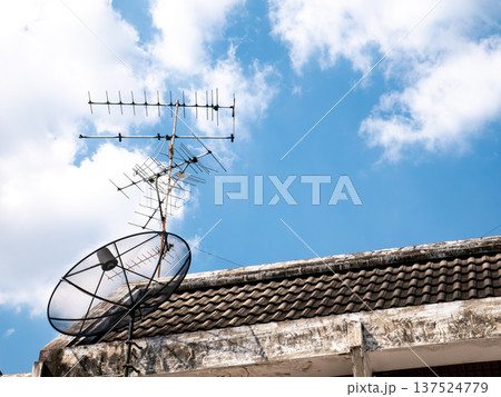 TV Antenna and Satellite Dish on Old Roof Against Blue Sky Background TV Antenna and Satellite Dish on Old Roof Against Blue Sky Background 137524779