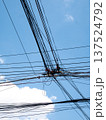 Messy Tangled Electrical Power Lines and Cables Against Blue Sky with Clouds 137524792