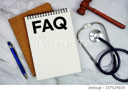 FAQ text written on notepad with stethoscope and gavel on marble background 137524810