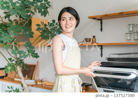 キッチンで電子レンジを使う女性（笑顔） 137527380