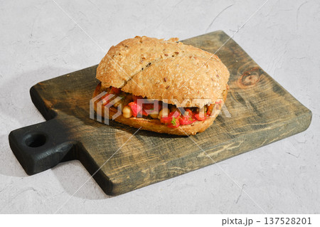 Roasted eggplant chickpeas and bell pepper sandwich on a wooden cutting board in a kitchen setting 137528201