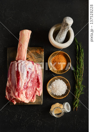 Raw meat prepared for cooking with spices and herbs on wooden board in kitchen setting 137528228