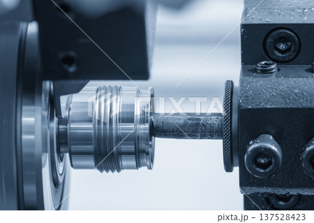 Close-up of a high-precision Swiss-type multi-tasking CNC lathe performing an internal boring process on a small metal screw component. 137528423