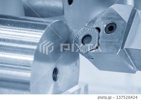 Close-up of a high-performance CNC lathe cutting tool performing a precision turning operation on a metal shaft in a modern industrial setting. 137528424