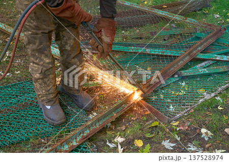 Worker cuts metal construction waste with a gas torch Worker cuts metal construction waste with a gas torch 137528974