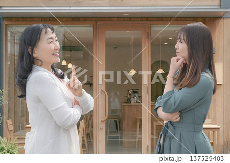 カフェの前で相談する二人の女性 カフェの前で相談する二人の女性 137529403
