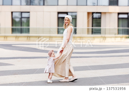 Beautiful happy mother and child walking together in city on summer. Full length Mom and baby outdoors 137531956