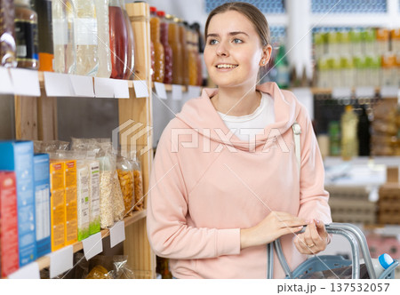 Woman in sweatshirt standing thoughtfully in store Woman in sweatshirt standing thoughtfully in store 137532057