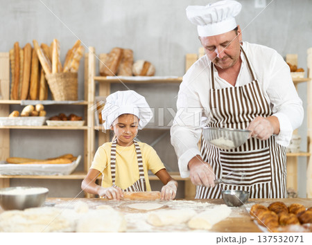 Bakers dad teaches daughter niece to work with dough, using rolling pin Bakers dad teaches daughter niece to work with dough, using rolling pin 137532071