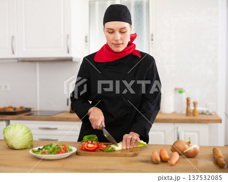 Portrait of positive woman chef cutting vegetables for salad 137532085