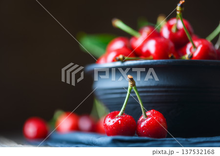 Ripe cherries near dark ceramic bowl on wooden table 137532168