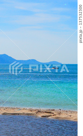 Bright blue sea with white sand beach on sunny day. Speed boat at Mountains distant on blue sky. 137532300