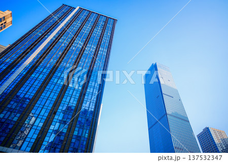 Glass tower building on blue sky background. Facade of new modern business office building. Glass tower building on blue sky background. Facade of new modern business office building. 137532347