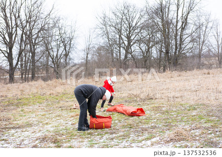 Exploring the wonders of nature as a child plays joyfully while an adult prepares outdoor gear on a chilly winter afternoon in a grassy field Exploring the wonders of nature as a child plays joyfully while an adult prepares outdoor gear on a chilly winter afternoon in a grassy field 137532536