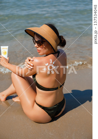 Beautiful woman enjoying sunny beach vacation with sunscreen lotion and suncream sun pattern 137534048