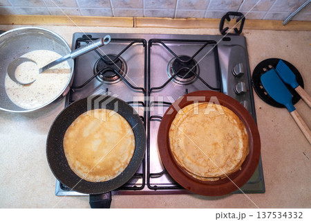 Pancakes cooking on gas stove with stack on plate Pancakes cooking on gas stove with stack on plate 137534332