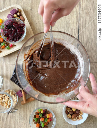 Women's hands whisking chocolate dough in a glass bowl. Baking, structure and consistency. Top view. 137534406