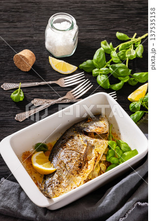 Baked whole dorada fish with lemon and basil 137535158