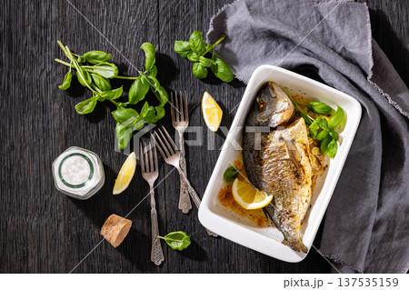 Baked whole dorada fish with lemon and basil 137535159