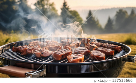屋外バーベキューで肉を焼く。鉄板の上には焼いた肉の煙が出ている。 137535666