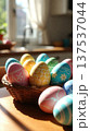 Basket of Pastel Easter Eggs on Sunlit Table 137537044