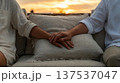 Couple Holding Hands on Sofa at Sunset 137537047