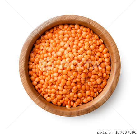 Red lentils in a wooden plate close-up on a white. Top view 137537396