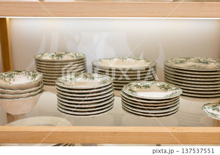 Elegant display of stacked vintage green and white ceramic plates on wooden shelves Elegant display of stacked vintage green and white ceramic plates on wooden shelves 137537551