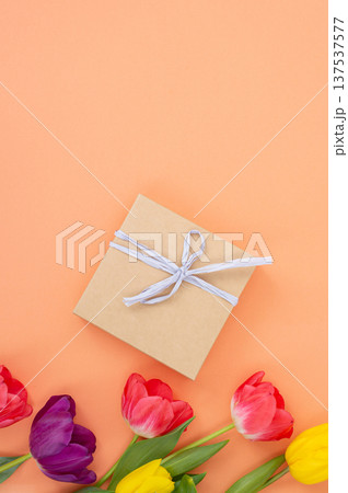Gift box on peach background with colorful tulips decor 137537577