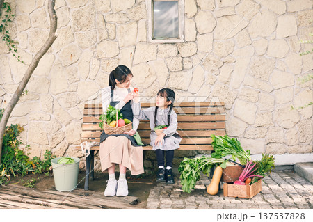 野菜を持ってベンチに座っている親子 137537828