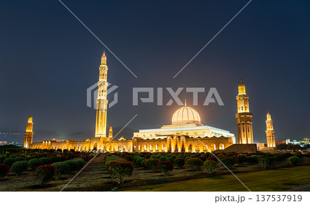 Illuminated view of the Sultan Qaboos Grand Mosque in Muscat, Oman, featuring its golden dome and tall minarets surrounded by landscaped gardens at night. Illuminated view of the Sultan Qaboos Grand Mosque in Muscat, Oman, featuring its golden dome and tall minarets surrounded by landscaped gardens at night. 137537919