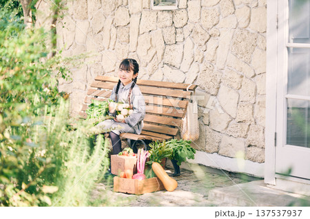 野菜を持ってベンチに座っている女の子 野菜を持ってベンチに座っている女の子 137537937