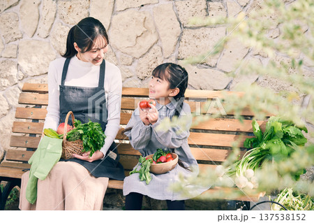 野菜を持ってベンチに座っている親子 137538152
