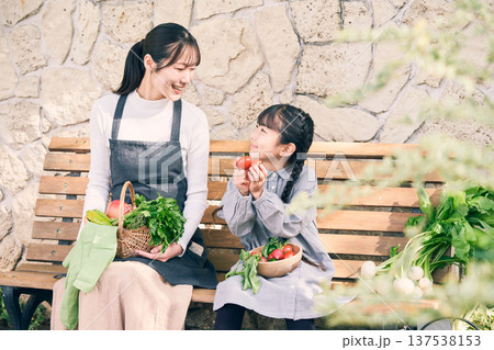 野菜を持ってベンチに座っている親子 137538153